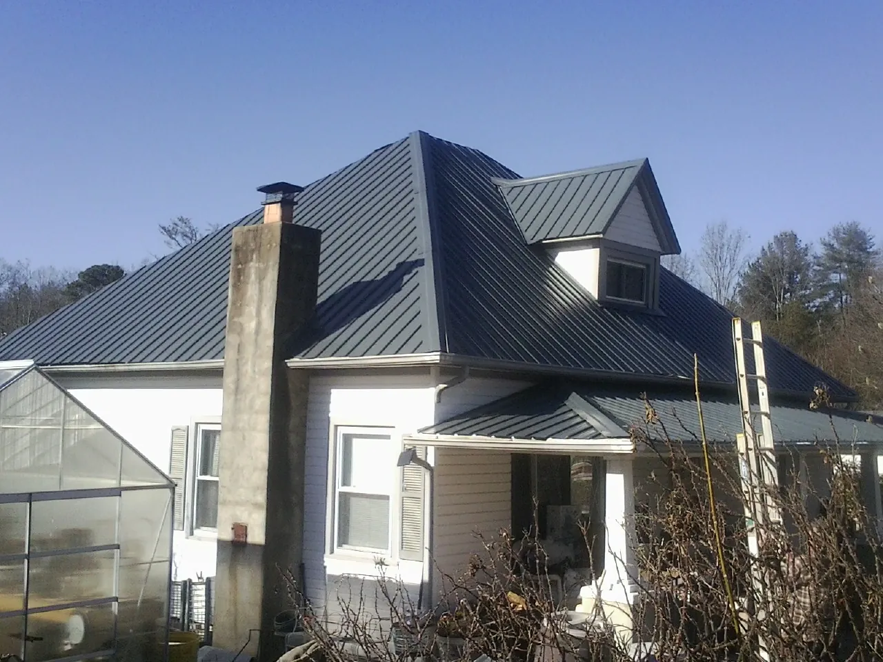 Dark blue standing seam metal roof on a white farmhouse with dormer — Slate & Tile Roof Repair by Roofing Brothers in Woodlyn