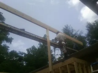 Carpenter setting a ridge beam over a new addition frame — Ice Dam Removal by Roofing Brothers in Woodlyn