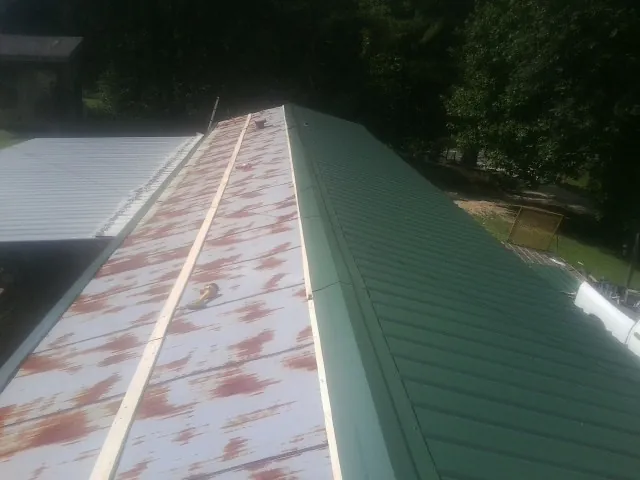 Old rusted panels beside newly installed green metal roofing — Wind Damage Roof Repair by Roofing Brothers in Woodlyn
