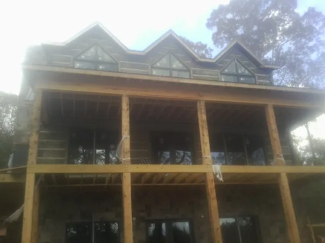 Dormers and porch framing on a large log home under construction — Roof Coating work by our crew in Woodlyn