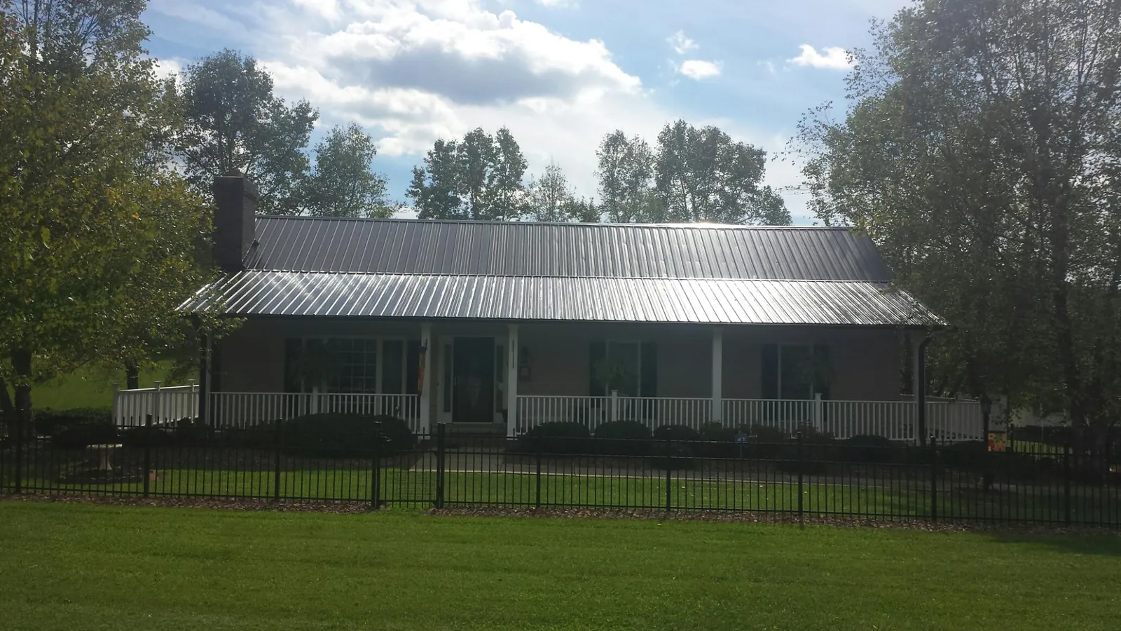 Gray metal roof on a brick ranch with a full width front porch — Gutter Guard Installation work by our crew in Woodlyn