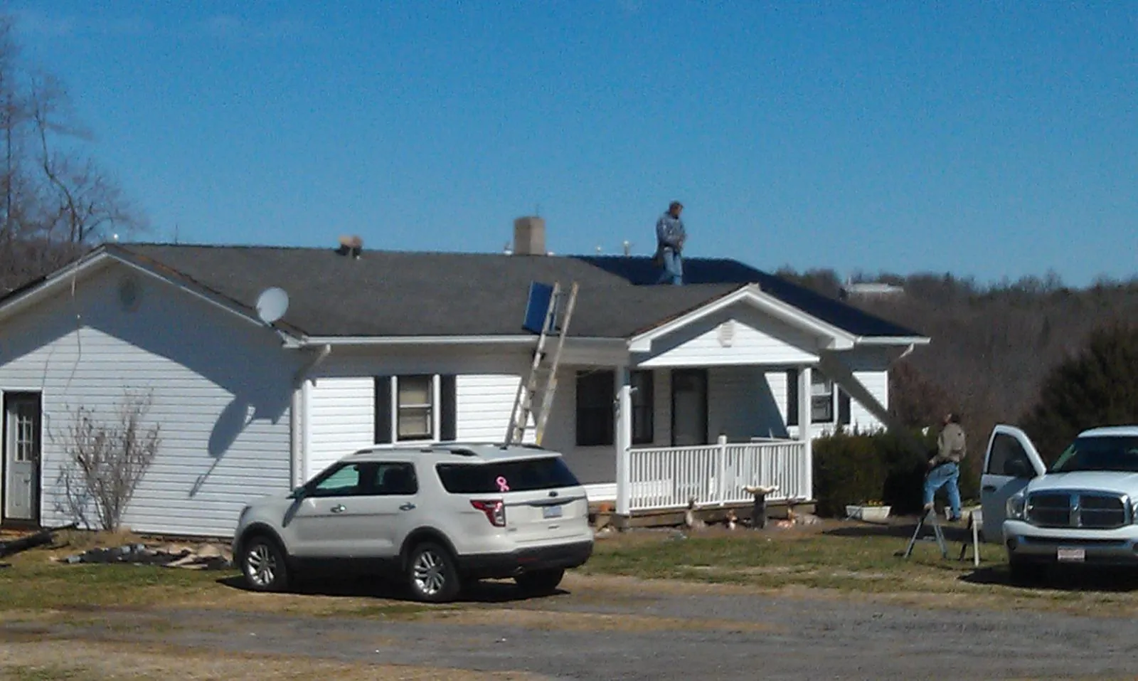 Roofers stripping shingles from a white ranch house roof in Woodlyn