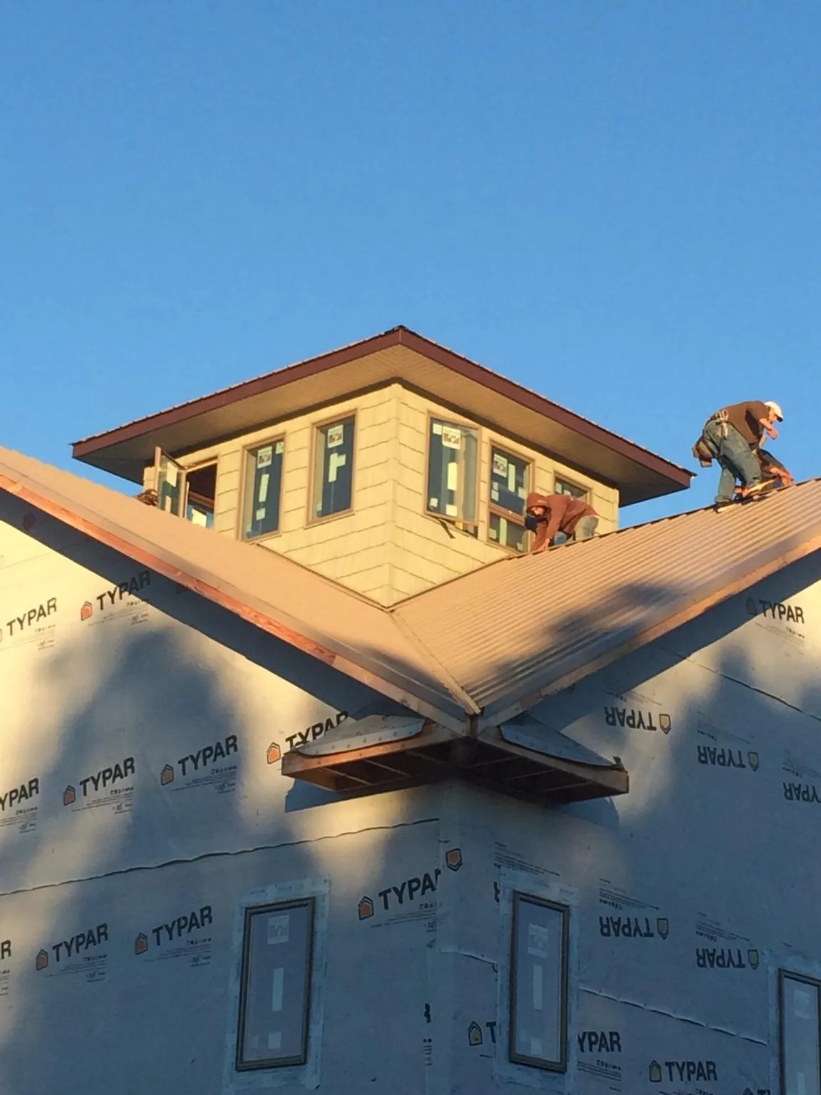 Roofers working around a rooftop cupola on a new metal roof at sunset — Roof Waterproofing in Woodlyn by Roofing Brothers